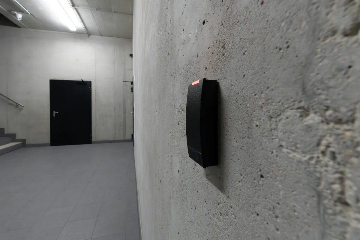 Proximity card reader on a wall beside a door in an office stairwell