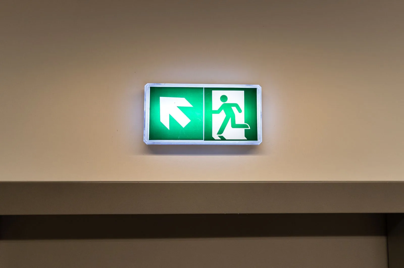 Illuminated green emergency exit sign showing a running figure and arrow