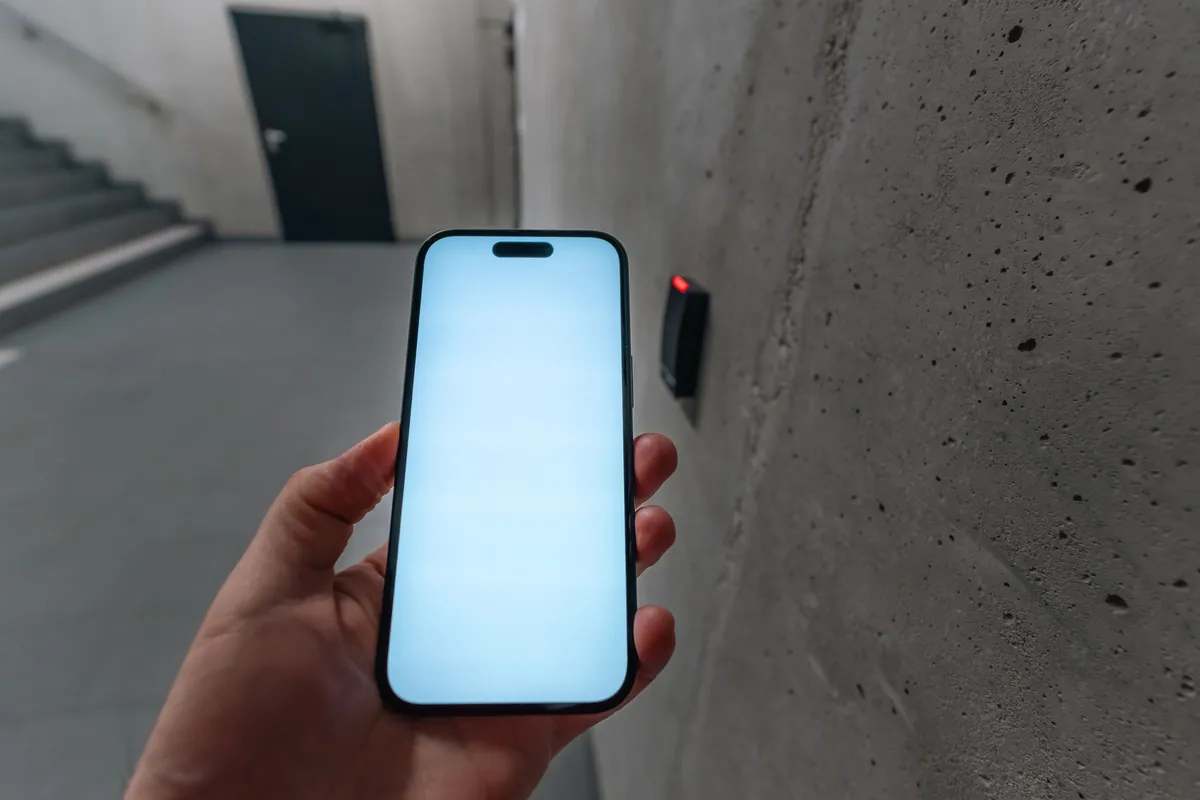 Person holding a smartphone up to a door reader to use a mobile credential