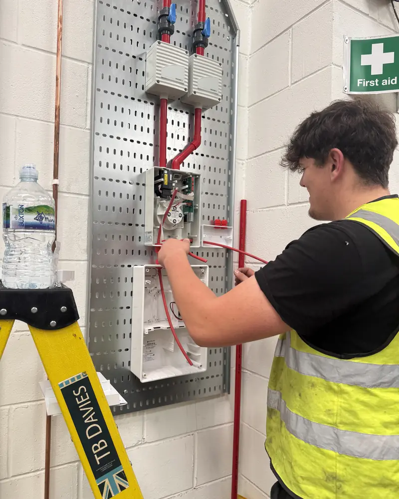 SAFE apprentice wiring aspirating smoke detection units on a backboard