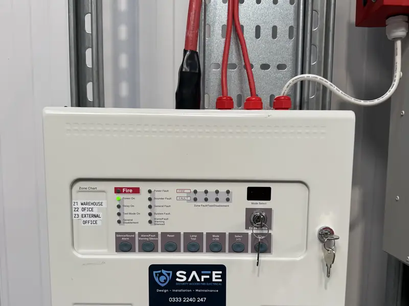 SAFE-installed conventional fire alarm panel in a warehouse with zone labels
