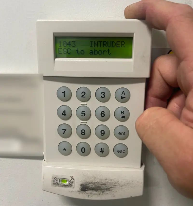 Intruder alarm keypad showing an intruder alert on its display